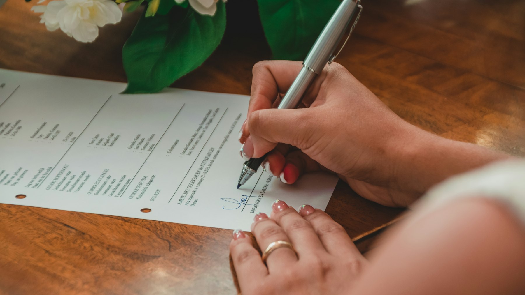Homeowner signing a printed real estate disclosure document at a wooden table