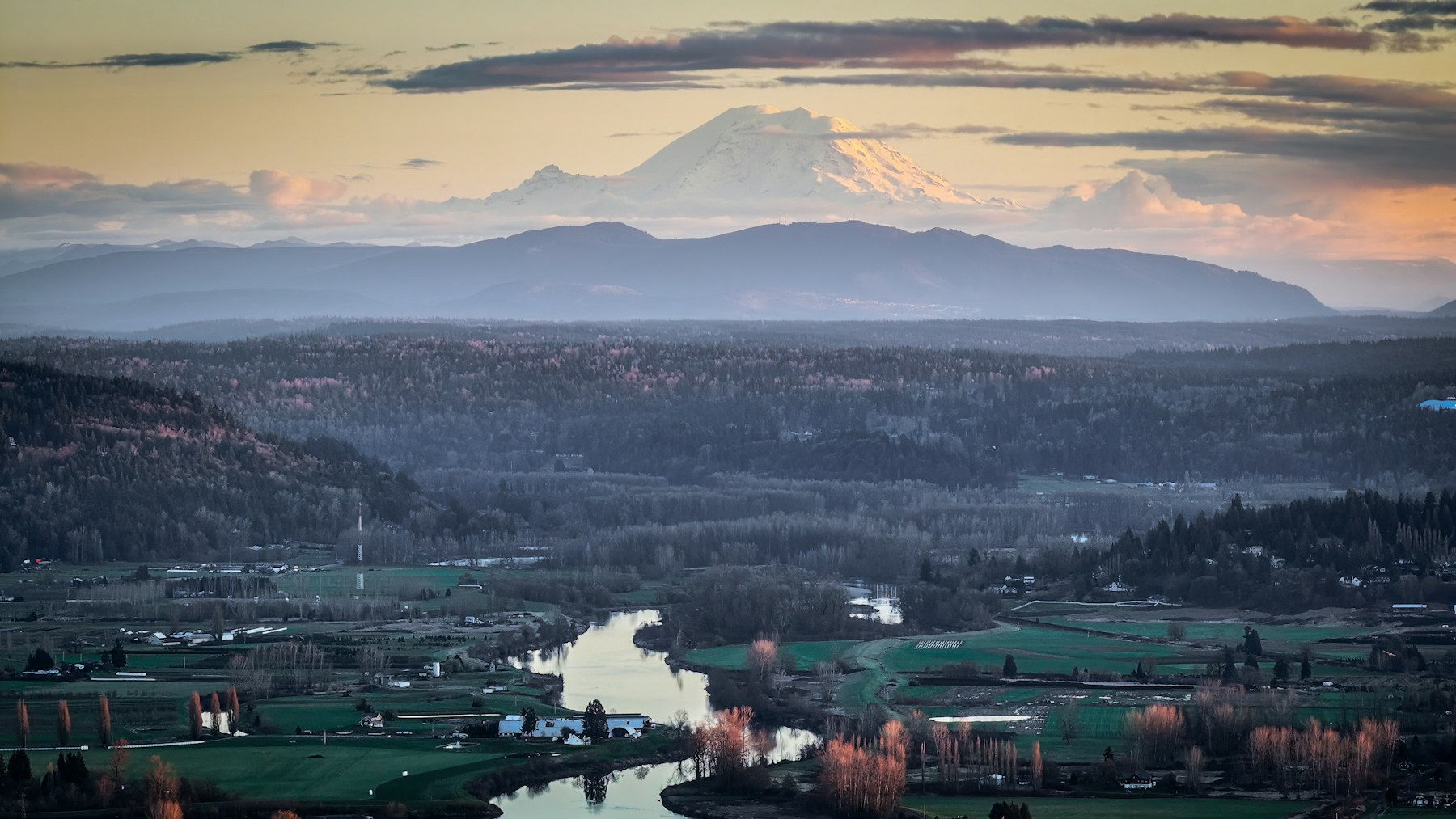 Rural river valley with farmland and forest in Western Washington, with Mount Rainier at sunset